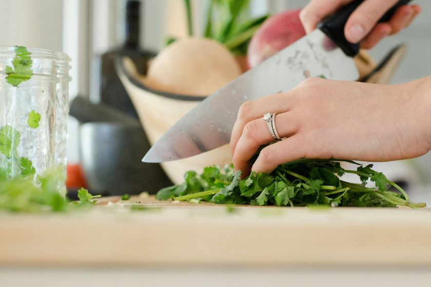 Someone cuts herbs on a cutting board.